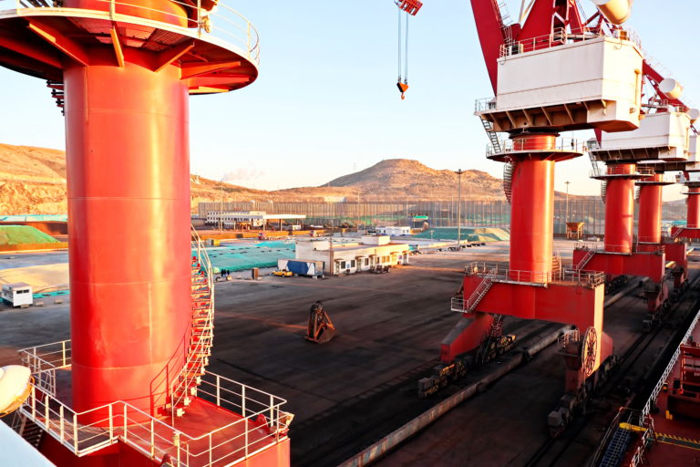 Cargo terminal for unloading bulk cargo of iron ore by shore cranes and grabs. Huludao, China, November, 2020.